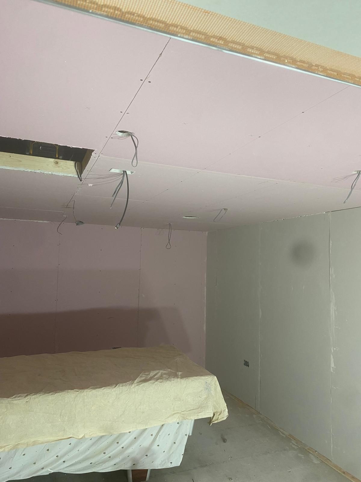 Drylined ceiling with pink plasterboard neatly fixed